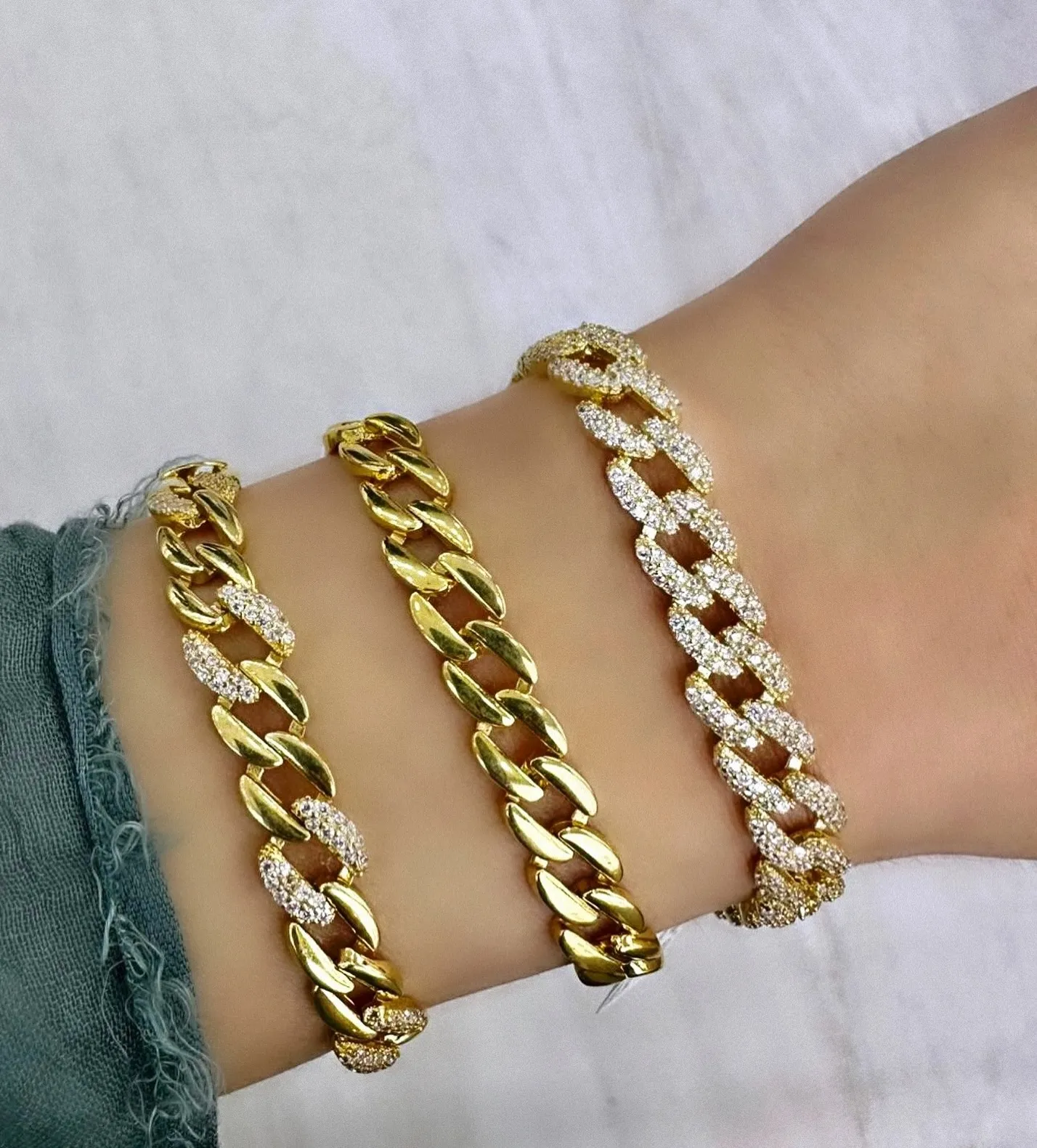 Drei goldene Panzerarmbänder, zwei davon mit Steinbesatz, am Handgelenk