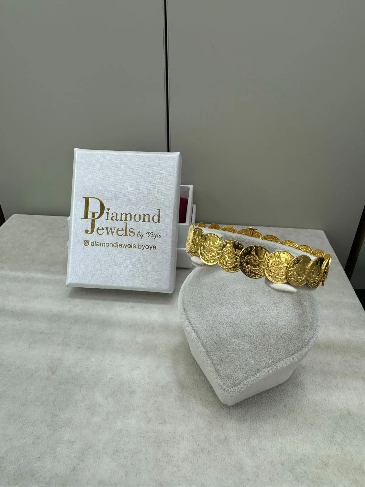 Goldarmband auf einem Samtständer vor einer Diamond-Jewels-Schachtel