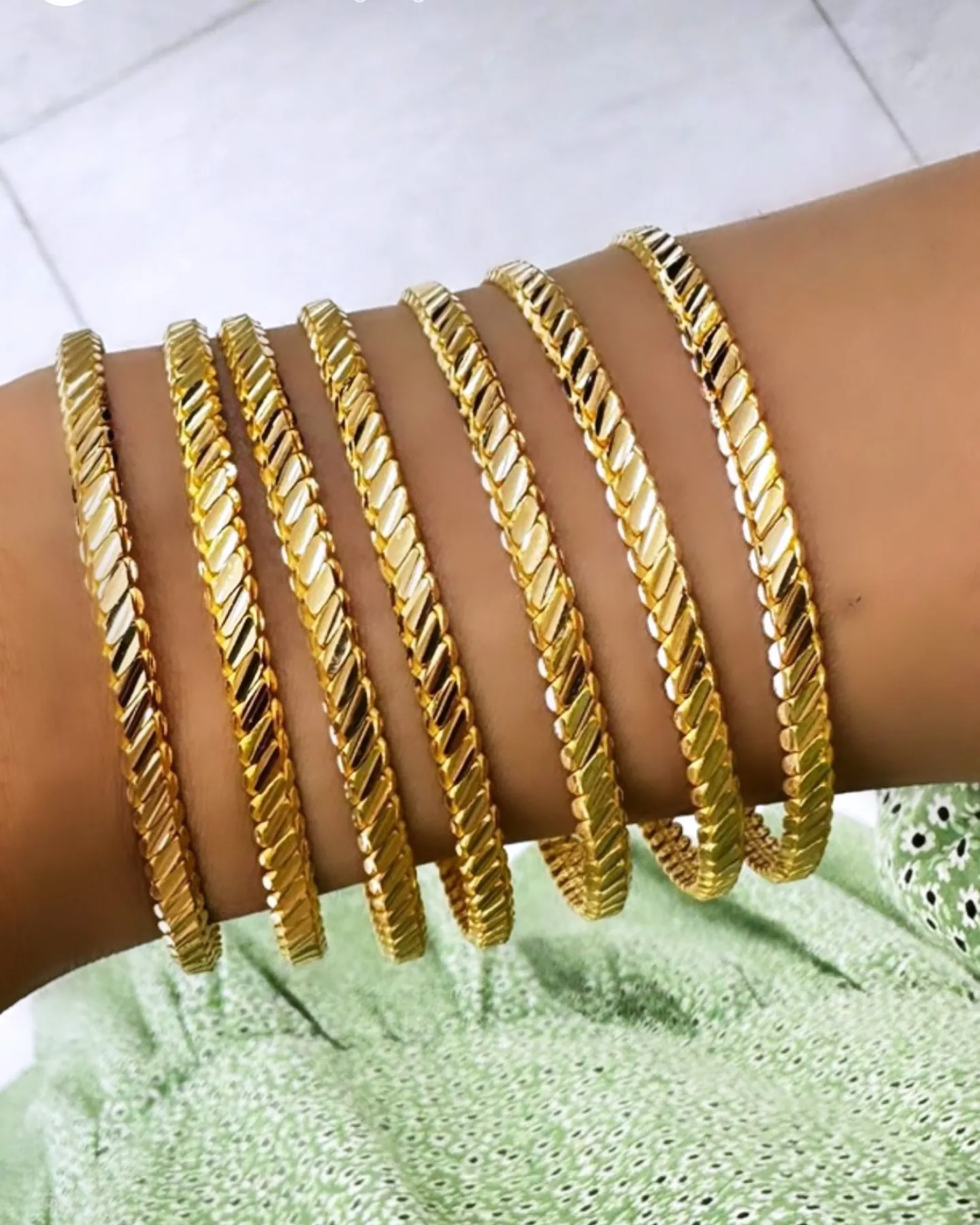 Mehrere gemusterte Armreifen aus 22 Karat Gold am Handgelenk
