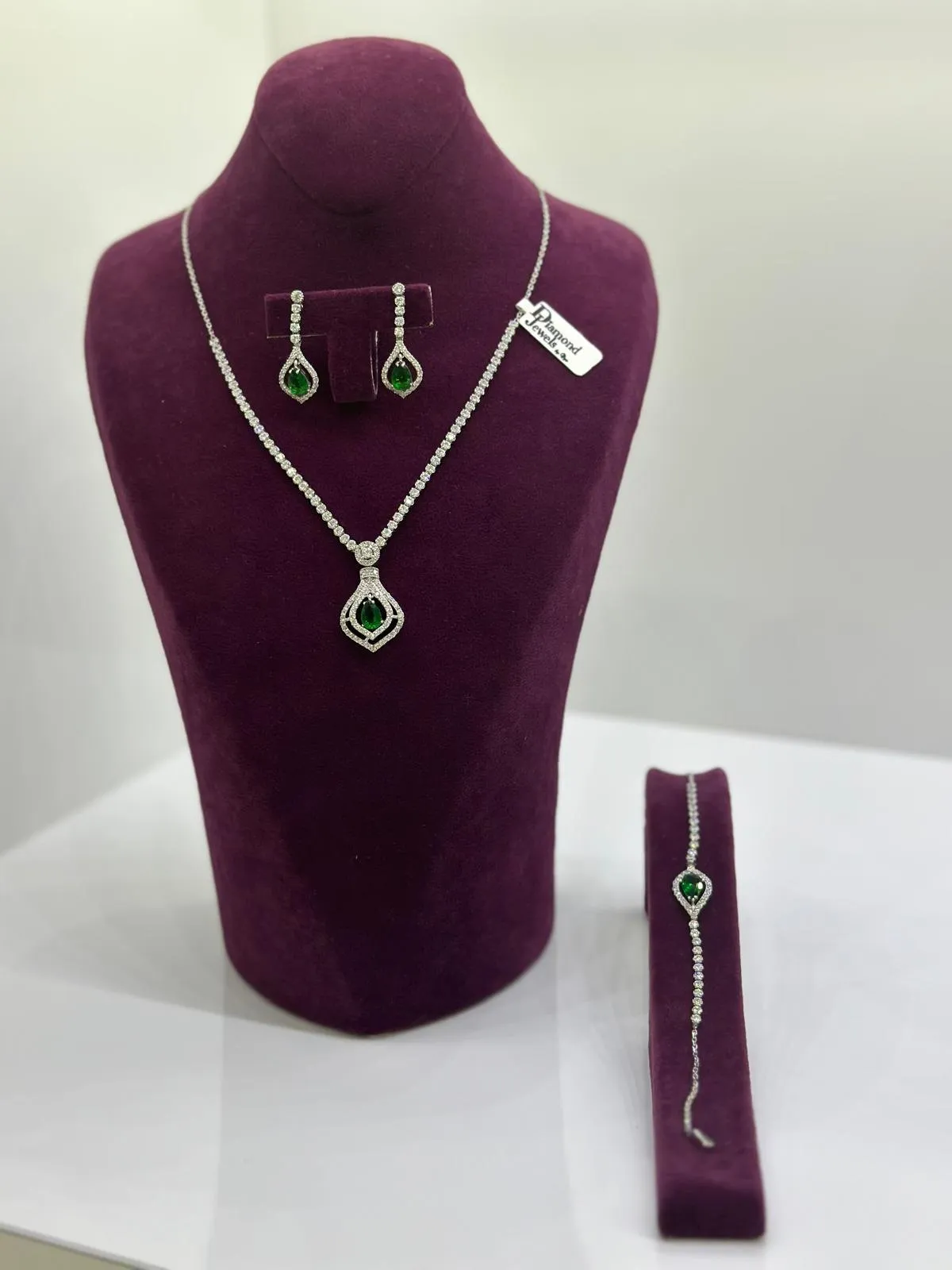 Collier mit grünen Steinen, passende Ohrringe und Armband auf einer Samtbüste