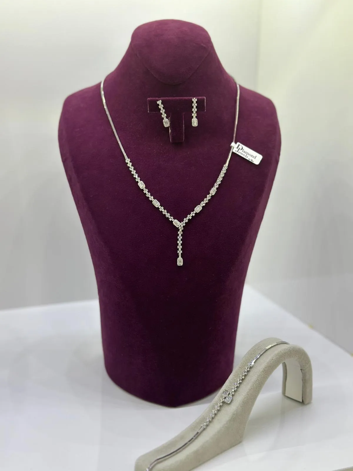 Y-Collier mit Steinbesatz und passenden Ohrringen auf einer Samtbüste