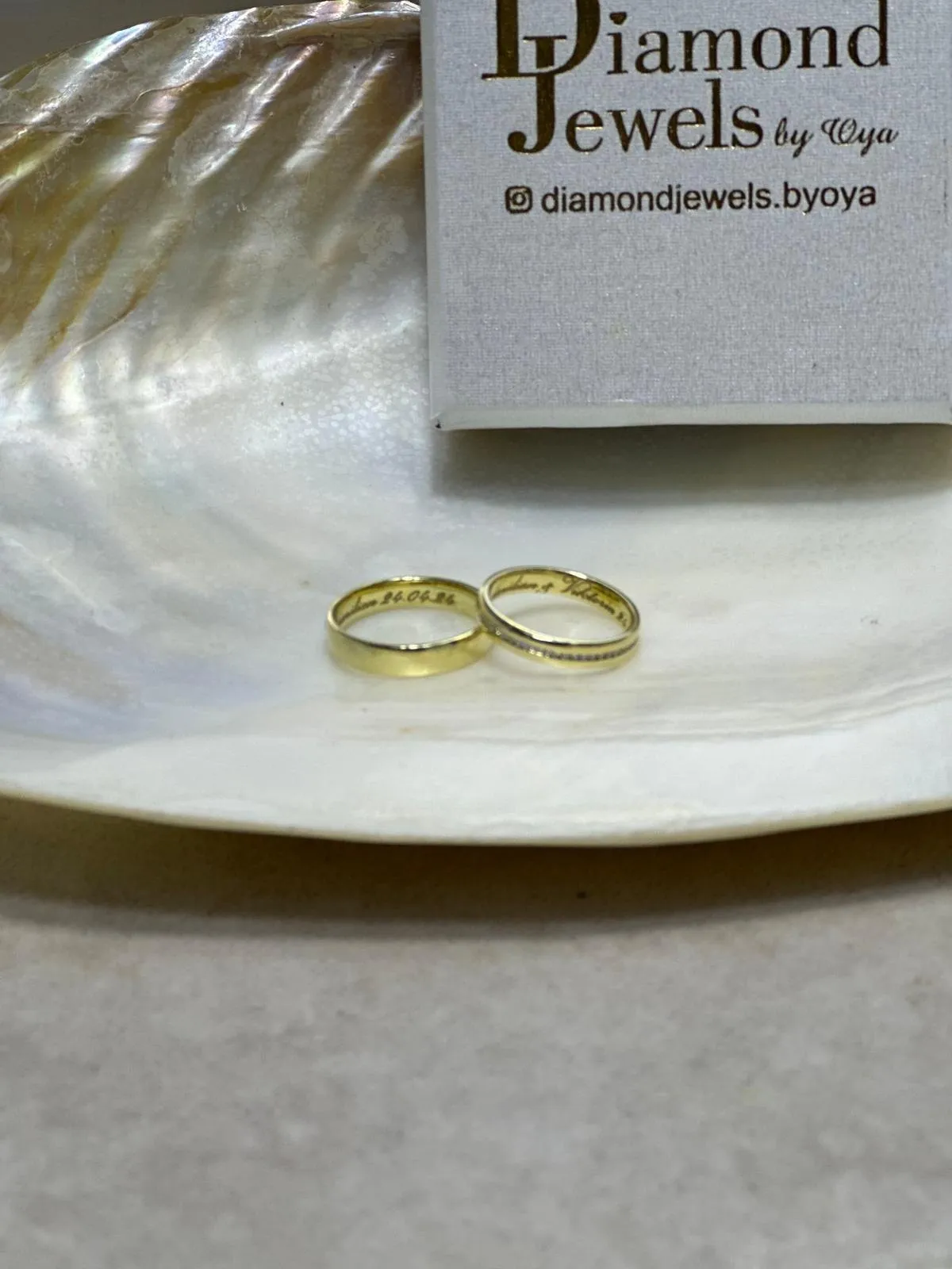 Zwei Eheringe aus Gelbgold mit Gravur in einer Perlmuttschale