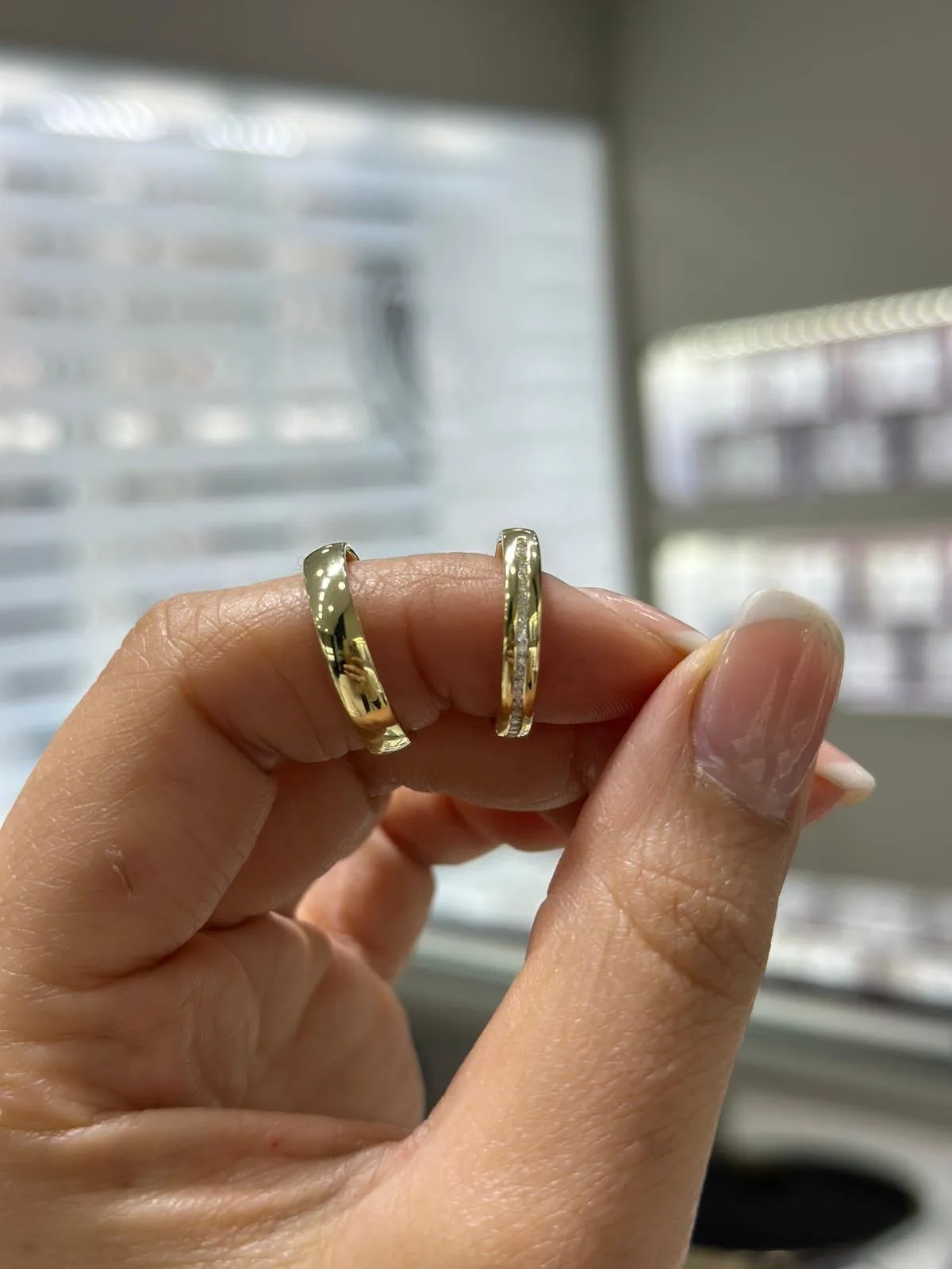 Zwei Eheringe aus Gelbgold zwischen zwei Fingern