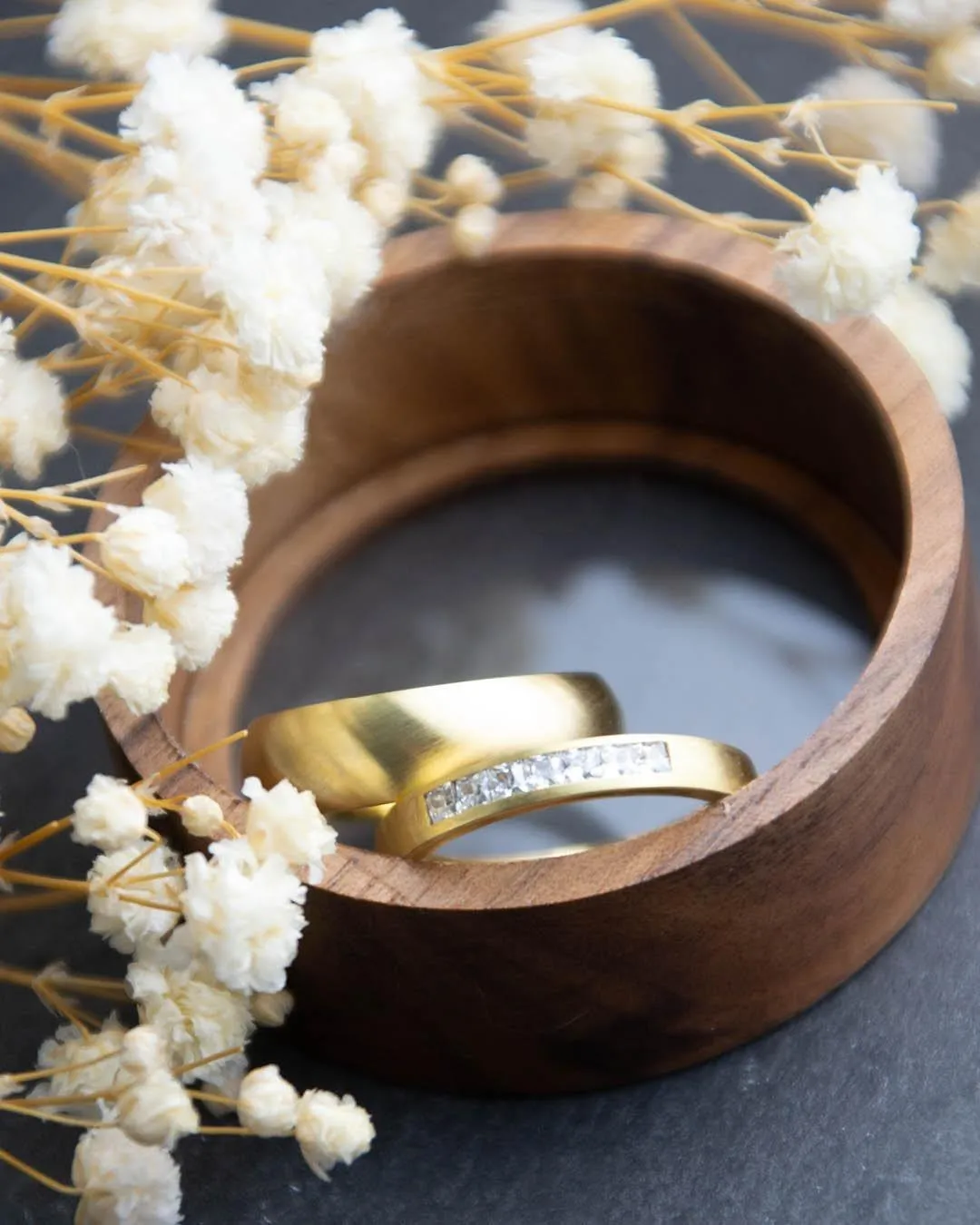 Eheringe in Gelbgold mit Steinbesatz in einer Holzschale