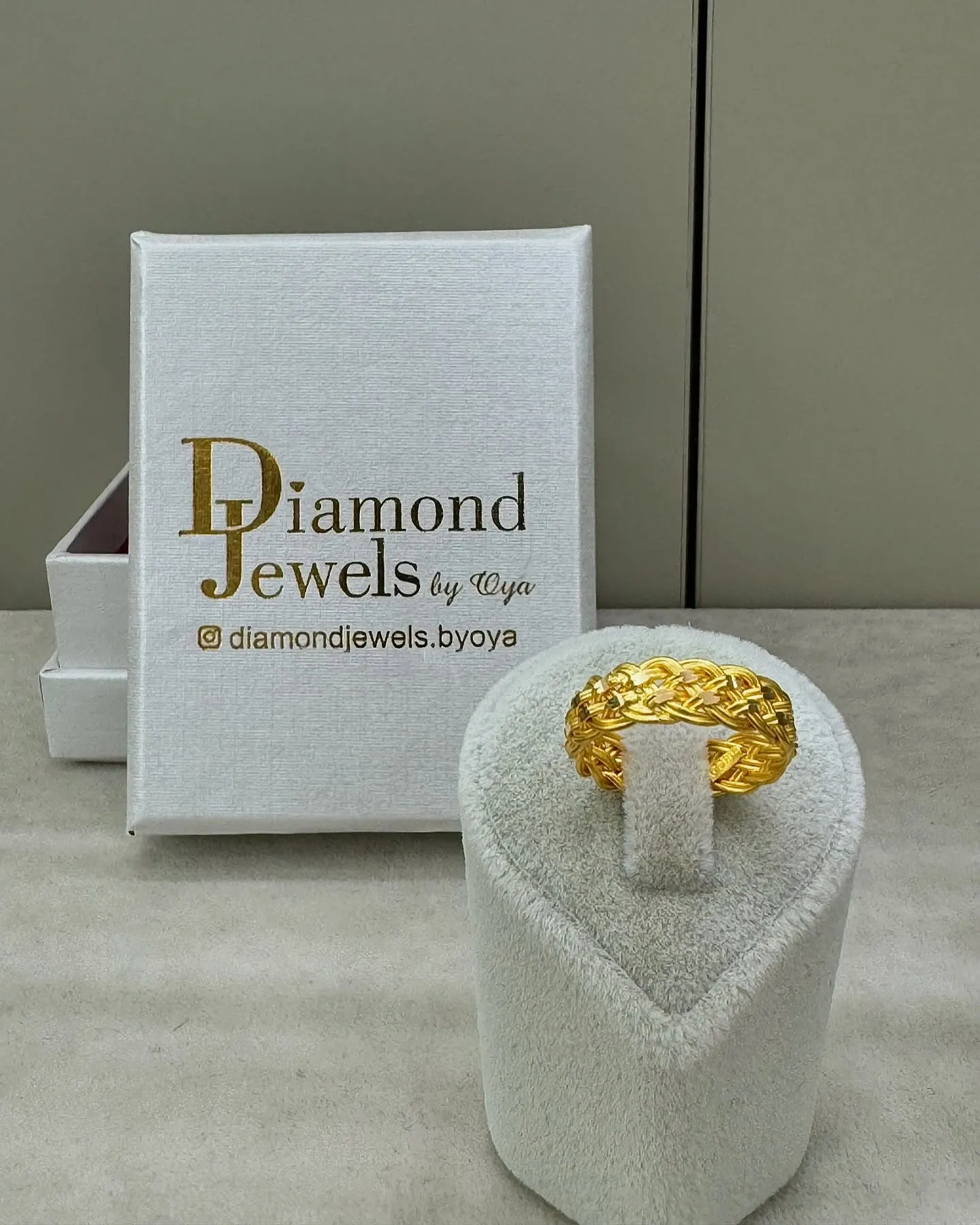 Goldring auf einem Ringständer vor einer Diamond-Jewels-Schachtel