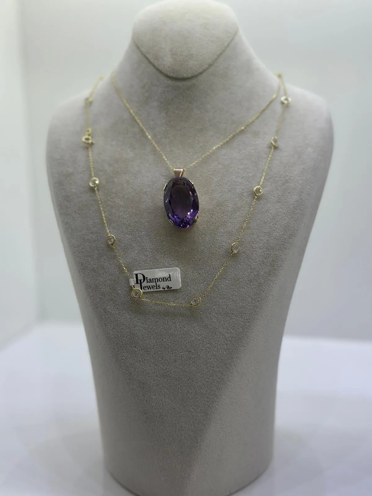 Kette mit großem violettem Anhänger auf einer hellen Büste