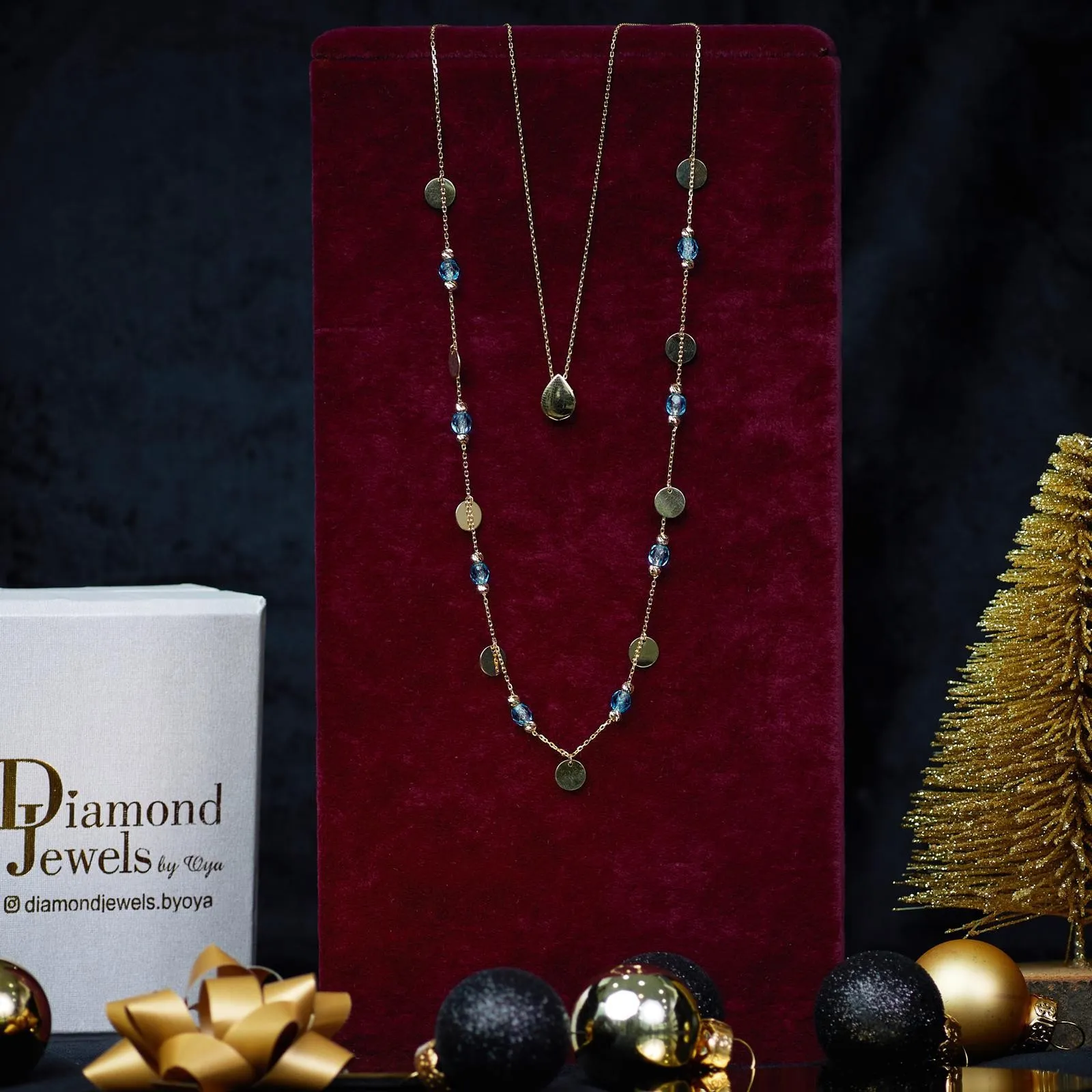 Lange Goldkette mit blauen Steinen und Plättchen auf rotem Samt
