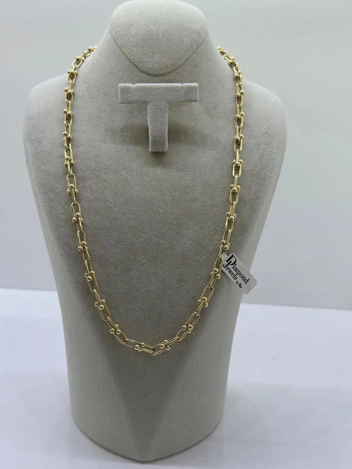 Goldene Gliederkette auf einer hellen Büste