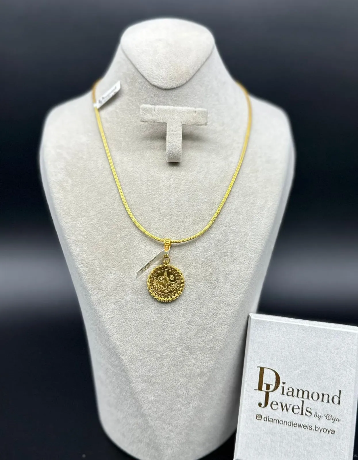 Goldkette mit Münzanhänger auf einer hellen Büste