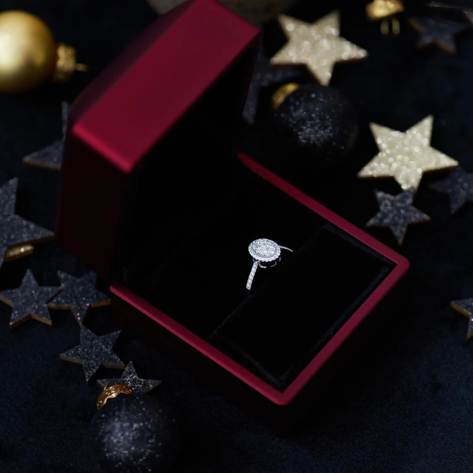Ring mit Steinkranz in einer roten Schmuckschatulle zwischen Sternen