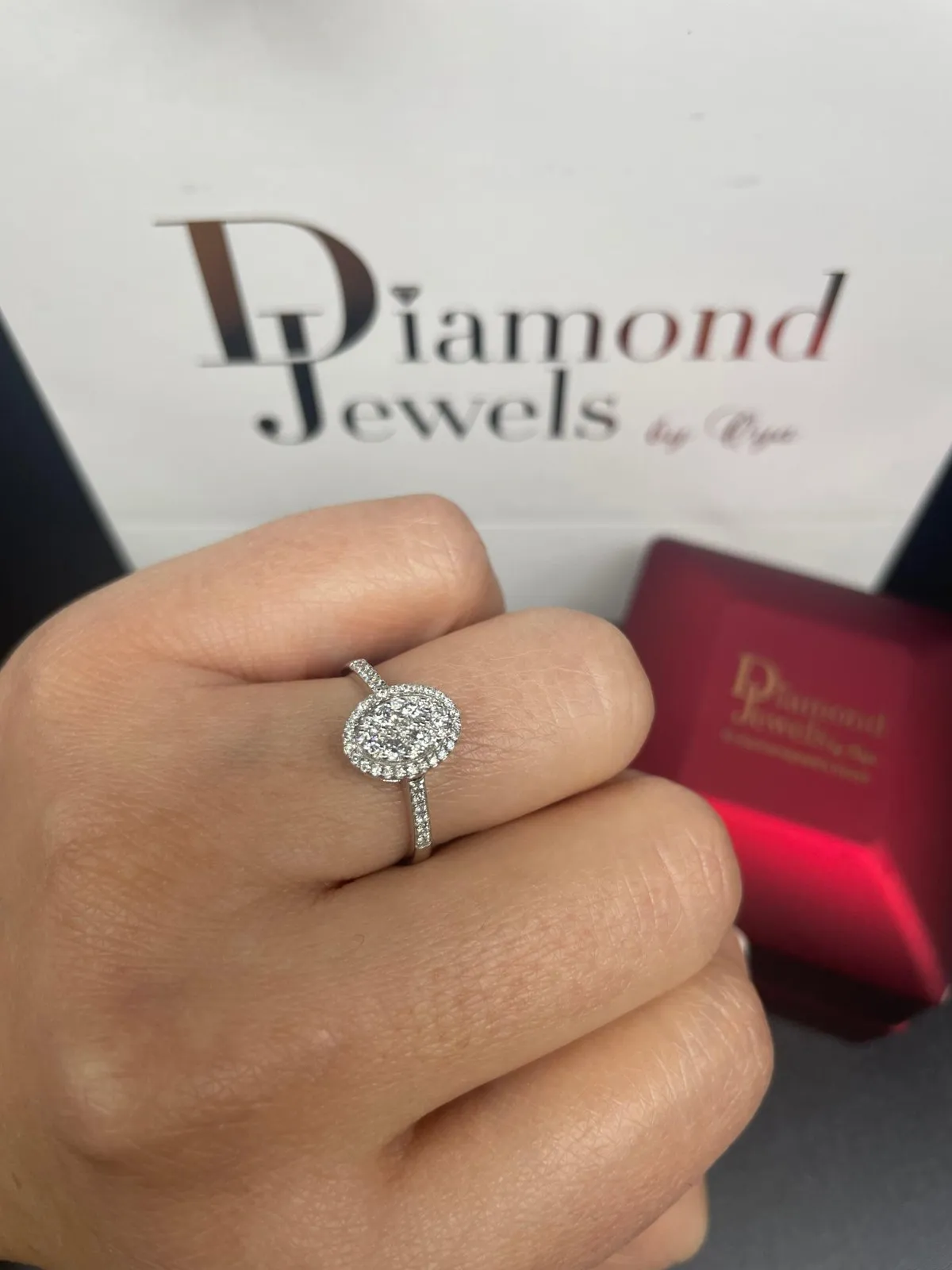 Ring mit ovalem Mittelstein und doppeltem Steinkranz an der Hand