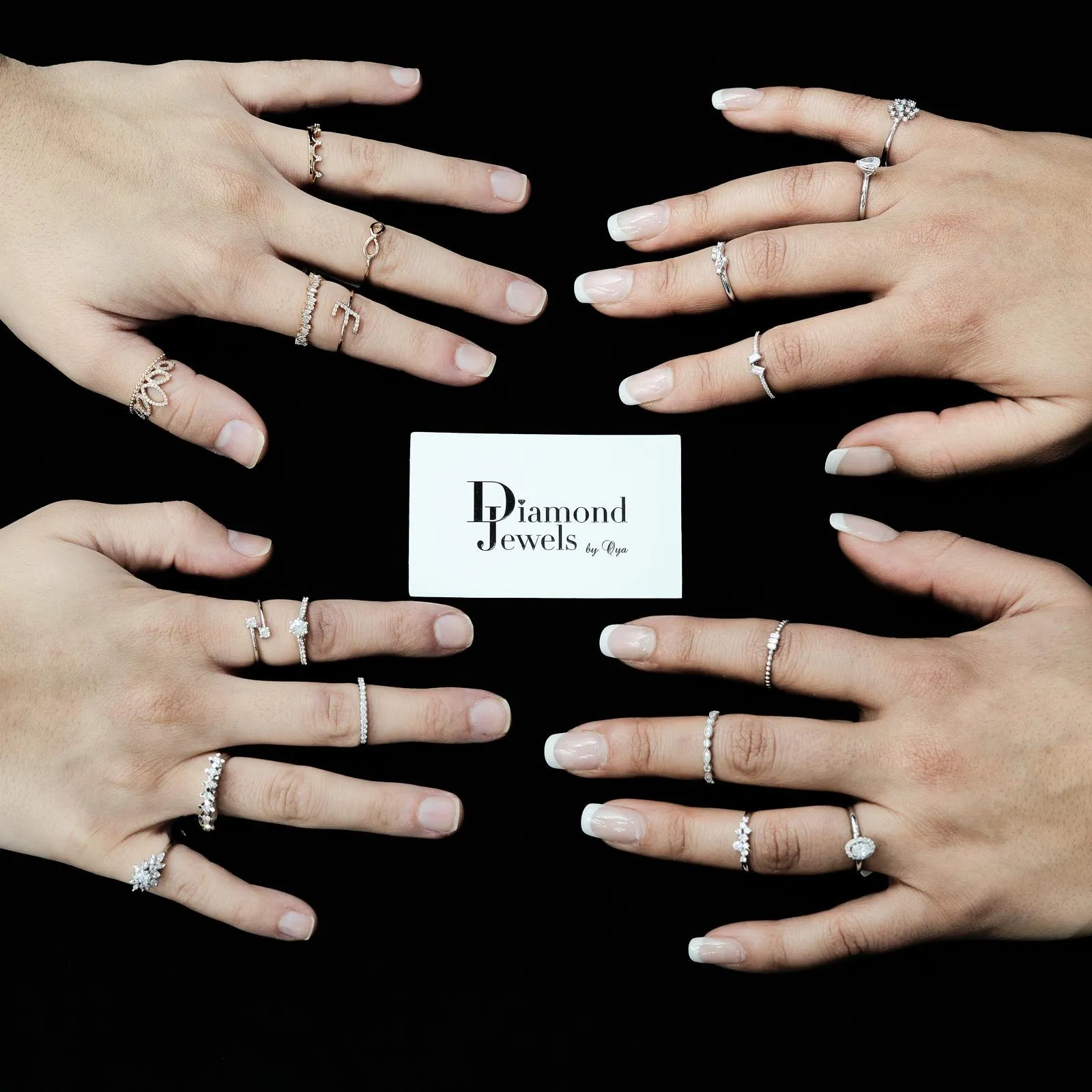 Vier Hände mit zahlreichen zarten Ringen um eine Diamond-Jewels-Karte